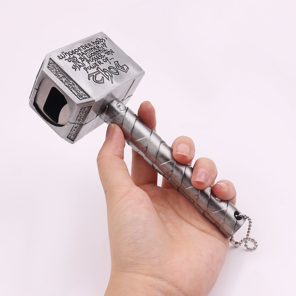 Décapsuleur Marteau de Thor argenté tenu en main, tête gravée et encoche décapsuleur, chaînette à billes