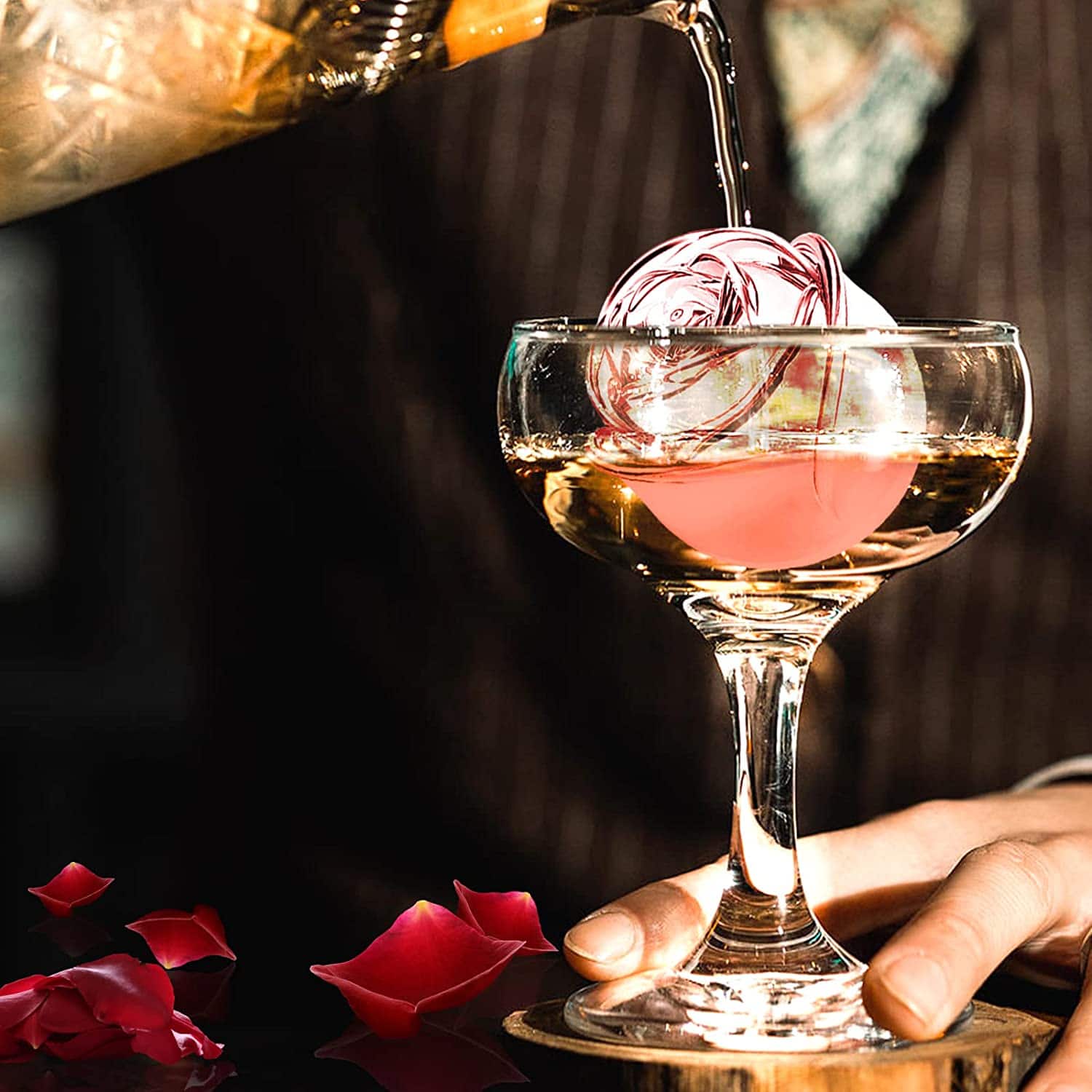 Glaçon rose translucide dans une coupe, champagne versé et pétales de rose rouges, ambiance romantique