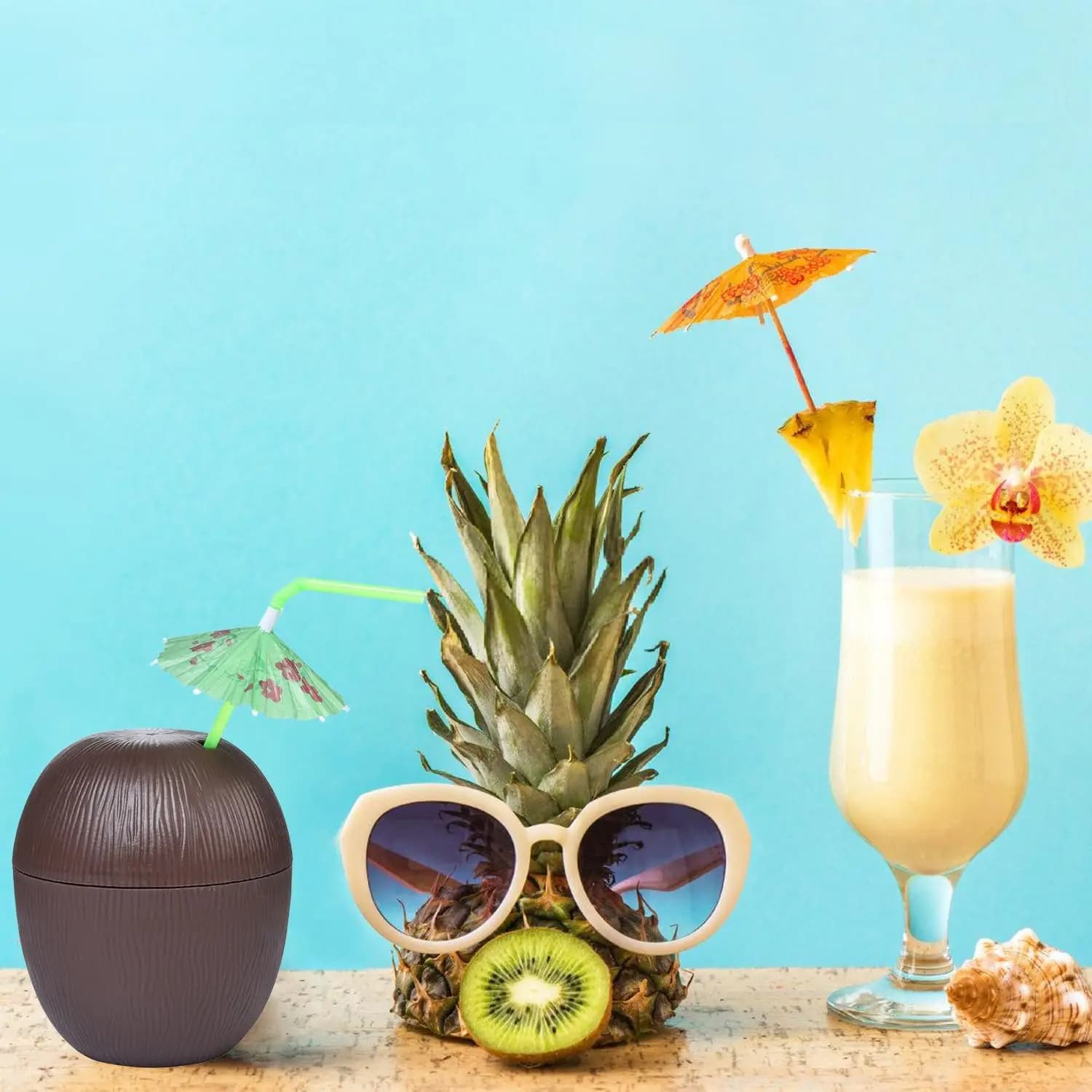 Verre noix de coco fermé avec paille verte et ombrelle, posé près d’un ananas à lunettes et d’une piña colada