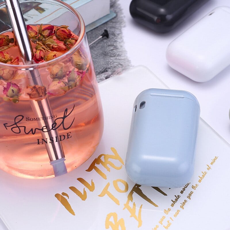 Étui bleu de paille en inox pliable posé près d'un verre de thé aux roses avec la paille inox plongée