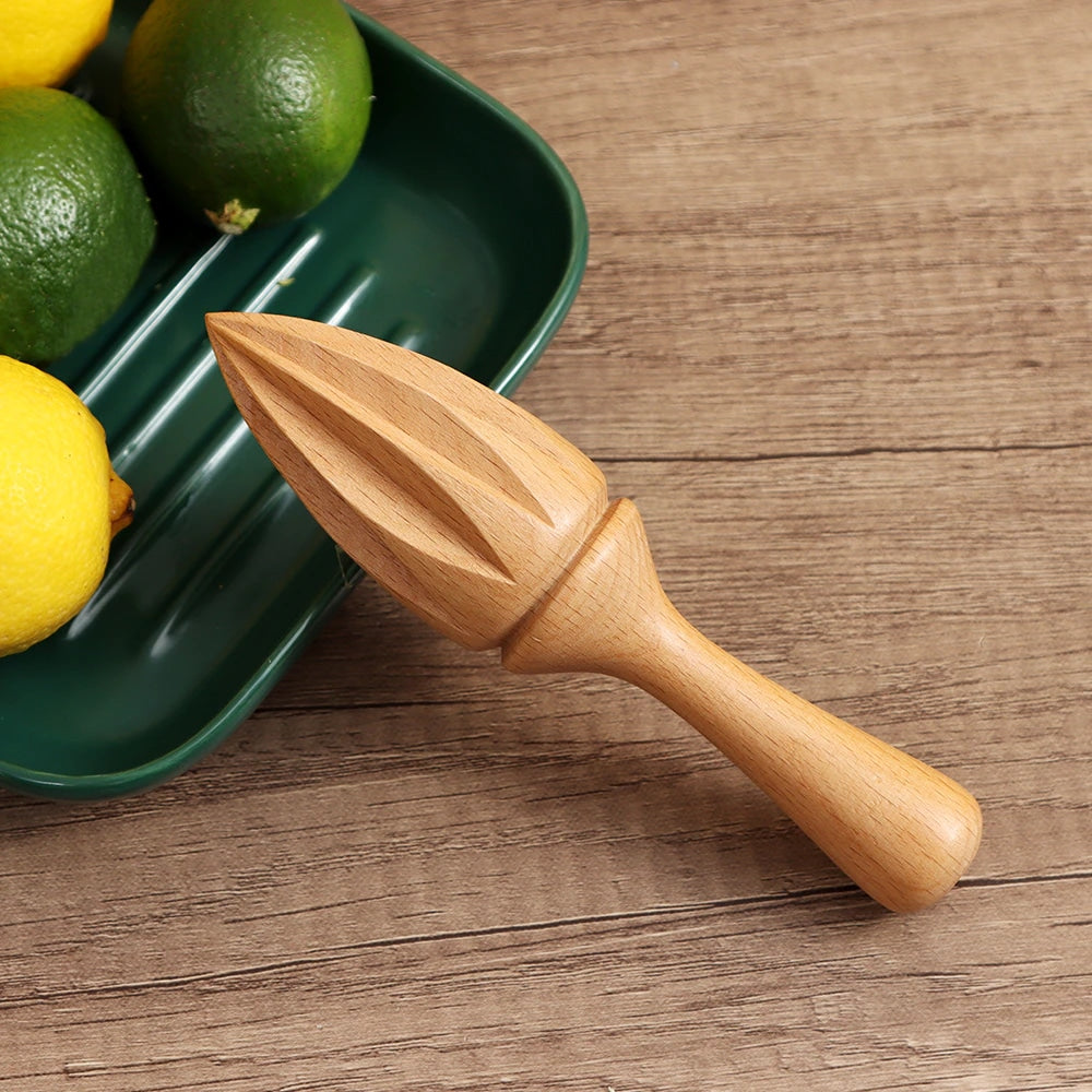 Presse agrume manuel bois posé près d'un plateau vert garni de citrons jaunes et citrons verts