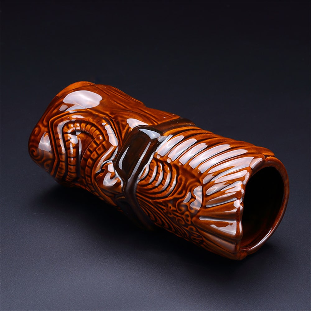 Verre Tikinator en céramique brune couché de profil, relief sculpté et ouverture visibles, fond gris