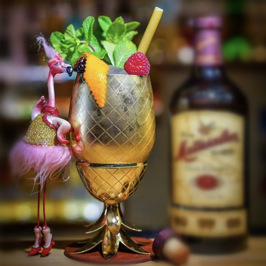 Verre Moscow Mule Ananas doré sur pied à feuilles, cocktail garni d'agrumes, framboise et menthe, déco flamant
