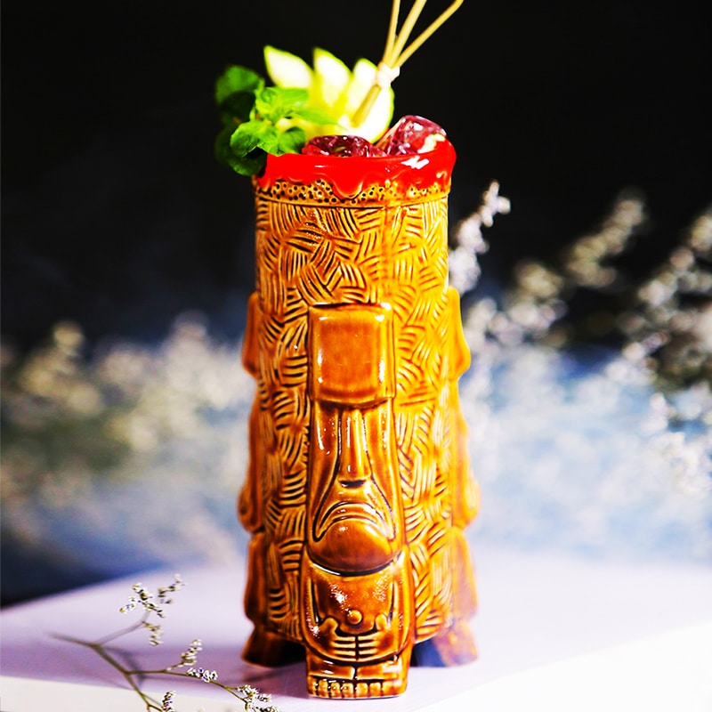 Verre tiki Bora Bora en céramique brune rempli d’un cocktail rouge glacé avec menthe, citron et pics décoratifs