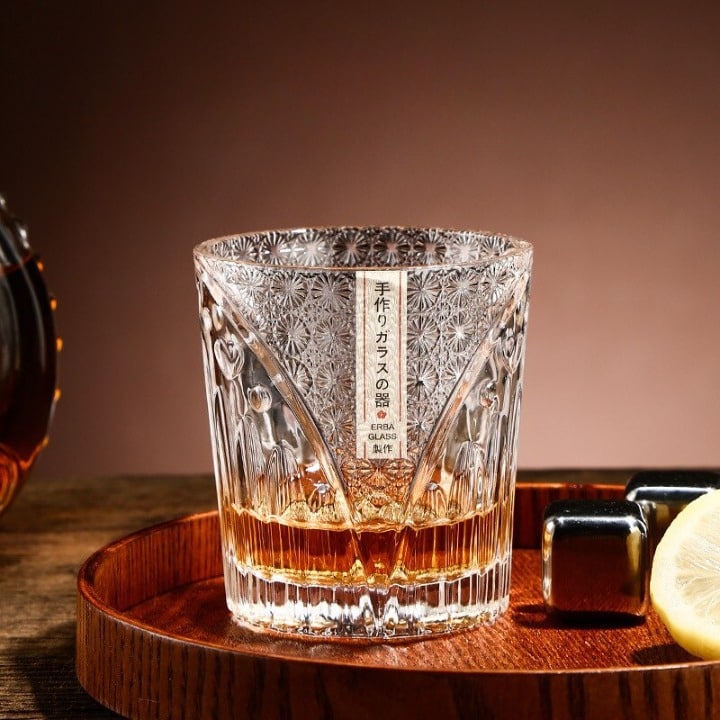 Verre whisky luxe en cristal ciselé posé sur un plateau en bois avec glaçons en inox et rondelle de citron