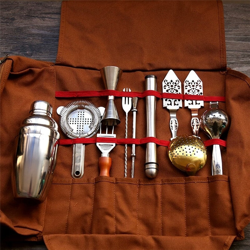 Trousse du kit cocktail voyageur déroulée à plat montrant l’ensemble des outils de barman en inox