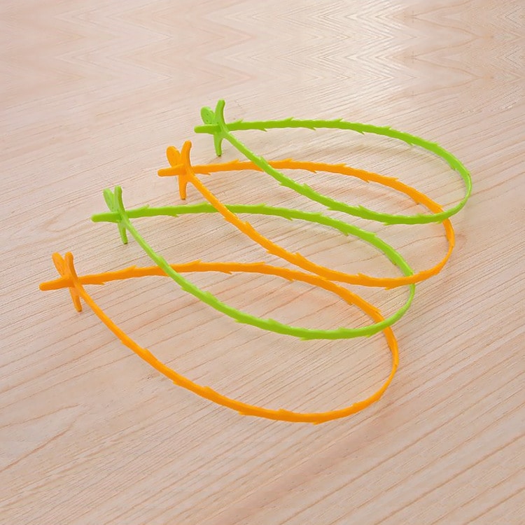 Quatre furets de Nettoyage pour Canalisation en plastique vert et orange à barbes, posés sur bois clair