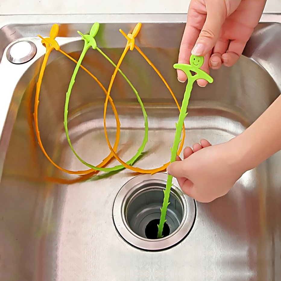 Brosse de Nettoyage pour Canalisation, furets flexibles verts et orange insérés dans une bonde d'évier inox