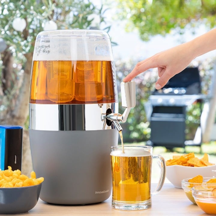 Distributeur de boisson pour particulier gris remplissant une chope de bière dans un jardin, snacks et barbecue autour