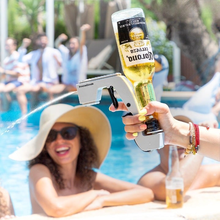 Pistolet à alcool monté sur une bouteille de bière, jet en action au bord d’une piscine