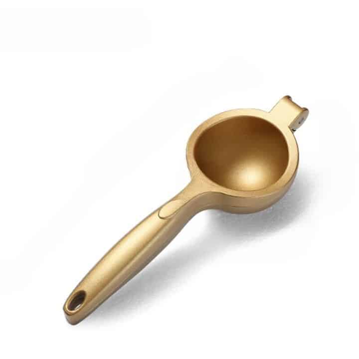 Presse citron design doré à bras et coupelle vu de dessus sur fond blanc, poignée à trou de suspension