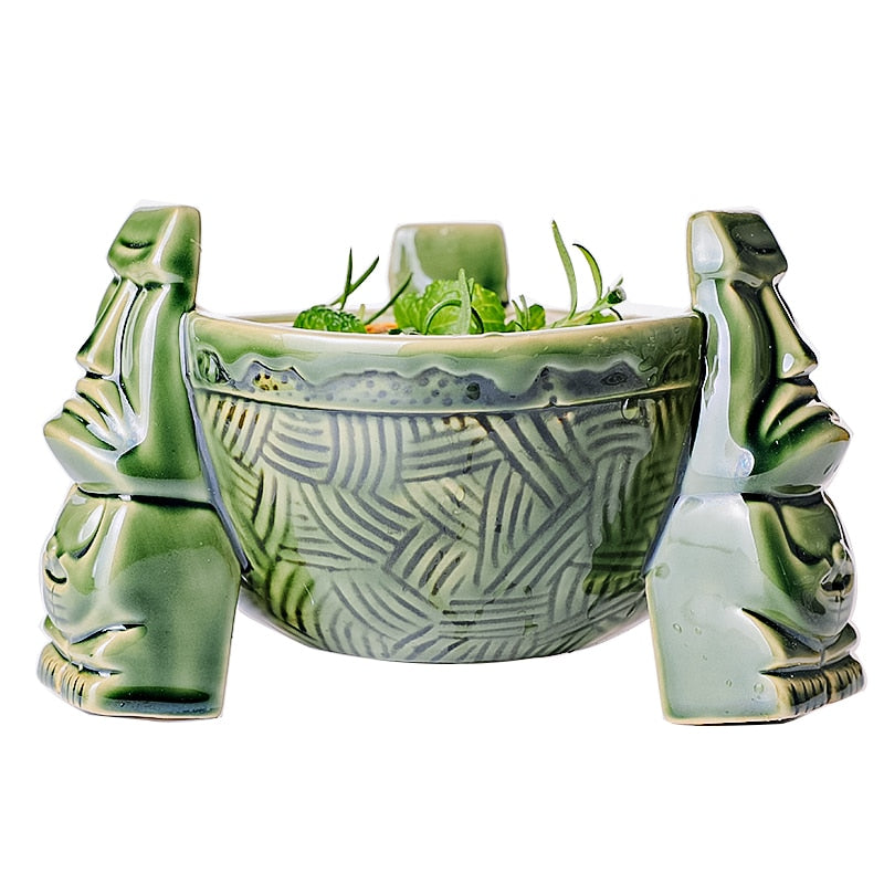 Récipient en céramique tiki vert rempli d’un cocktail garni d’herbes fraîches, vue de face