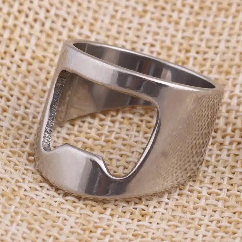 Bague Décapsuleur argentée en acier inoxydable posée sur une toile de jute beige, encoche visible