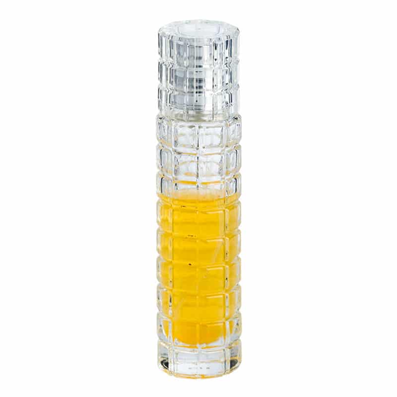 Spray pulvérisateur culinaire en verre texturé rempli d'huile jaune, capuchon fermé sur fond blanc