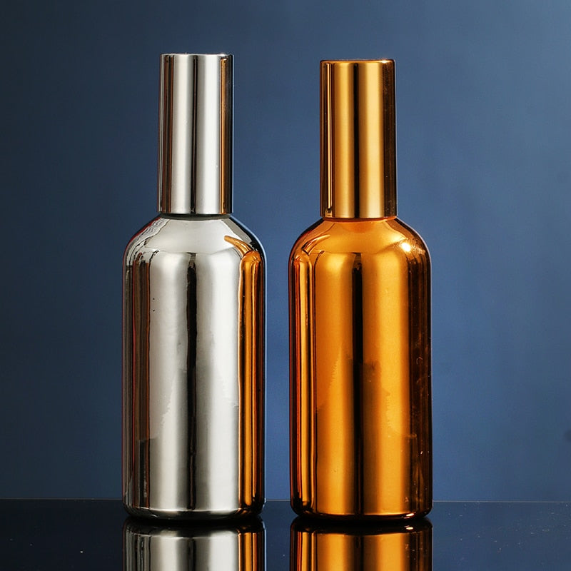 Spray pulvérisateur culinaire design en verre finition argent et or côte à côte sur fond bleu