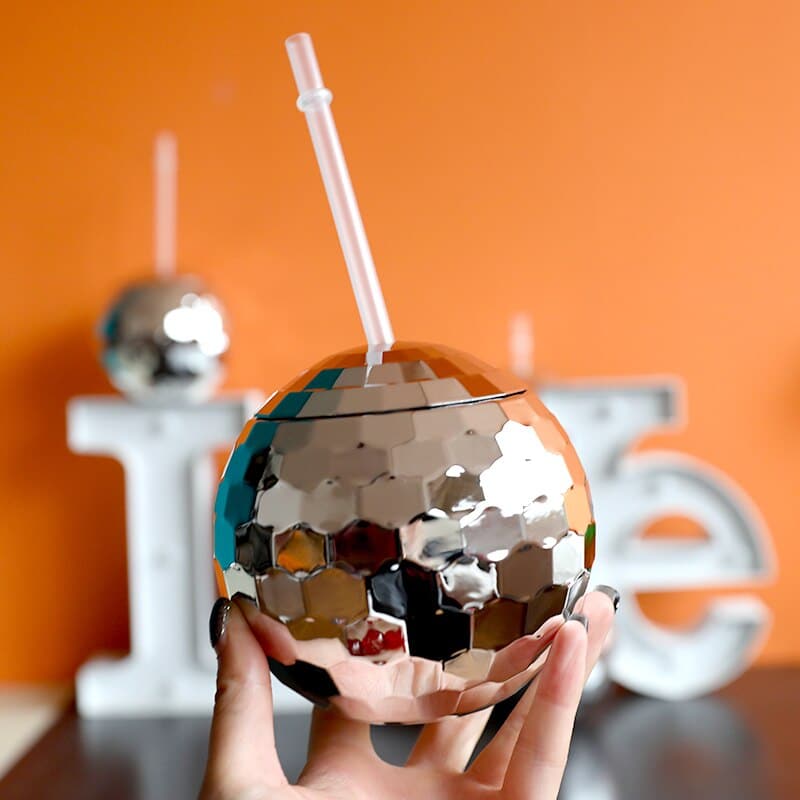 Verre à Cocktail Disco boule à facettes miroir tenu à la main avec paille, fond orange et lettres lumineuses