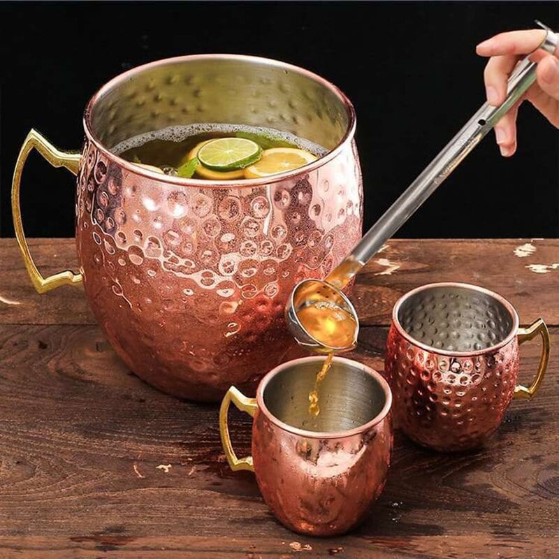 Verre Moscow Mule Géant cuivré martelé rempli de punch avec louche, deux petits mugs assortis à côté