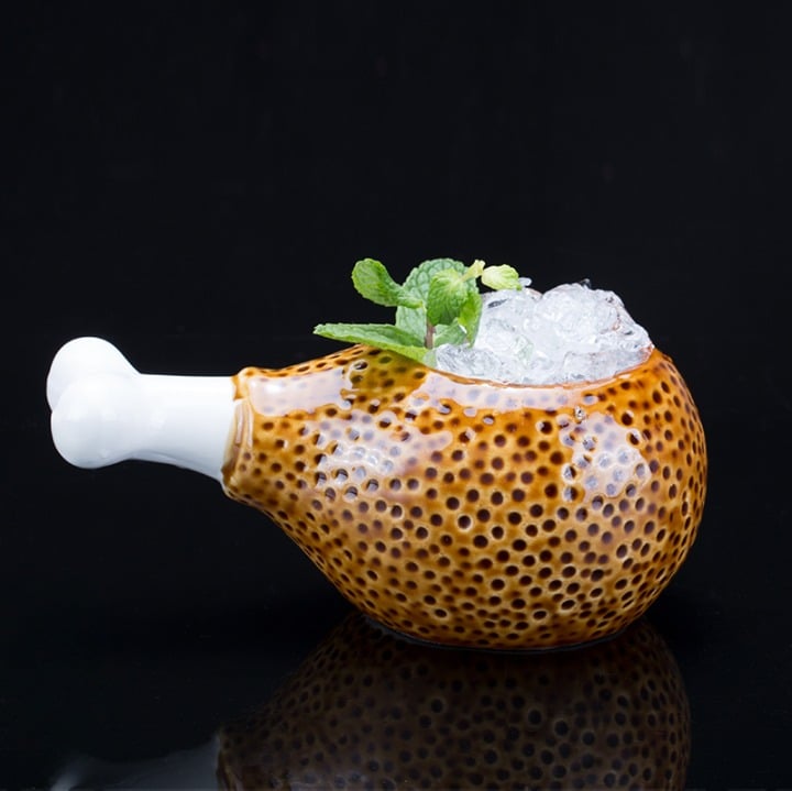 Verre Original Cuisse rempli de glace pilée et menthe, céramique façon pilon, manche os, fond noir