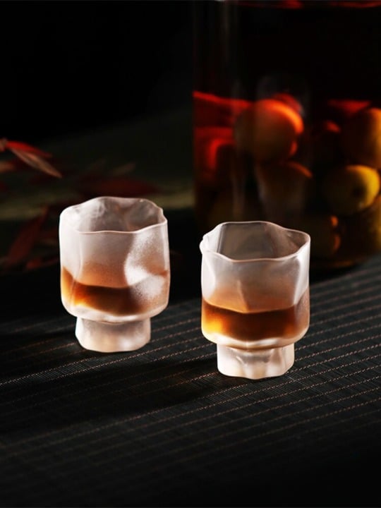 Verre Shooter Design givré à surface bosselée, deux verres remplis d'alcool ambré sur natte sombre