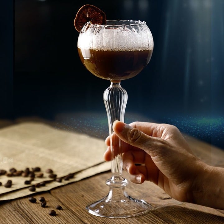 Verre à Cocktail Vintage à pied haut, cocktail café mousseux, agrume séché et grains de café sur table en bois