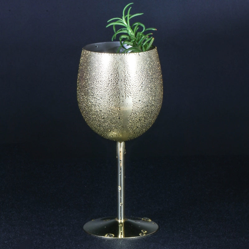 Verre à vin original doré perlé de condensation, garni d’une branche de romarin