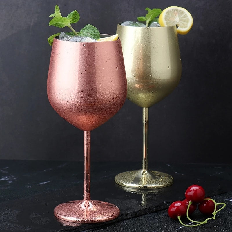 Verre à vin original rose gold et verre doré remplis de glaçons, menthe et citron, posés sur une ardoise avec des cerises